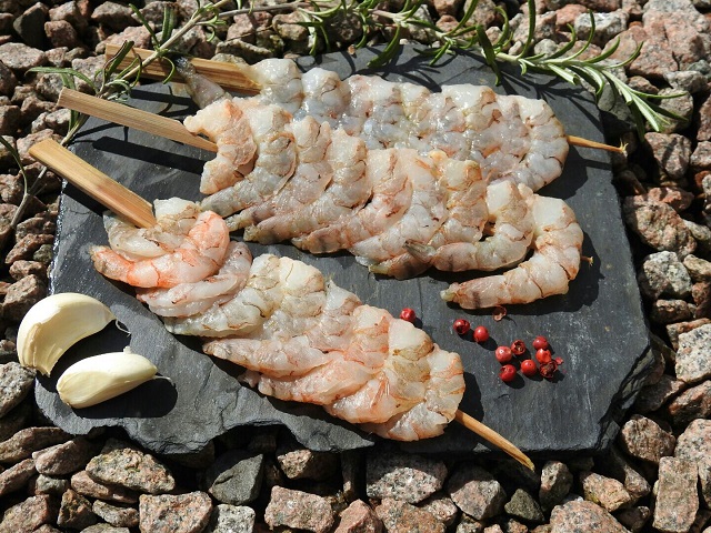 Gegrillter Garnelenspieß mit Kräutern auf einer Schieferplatte