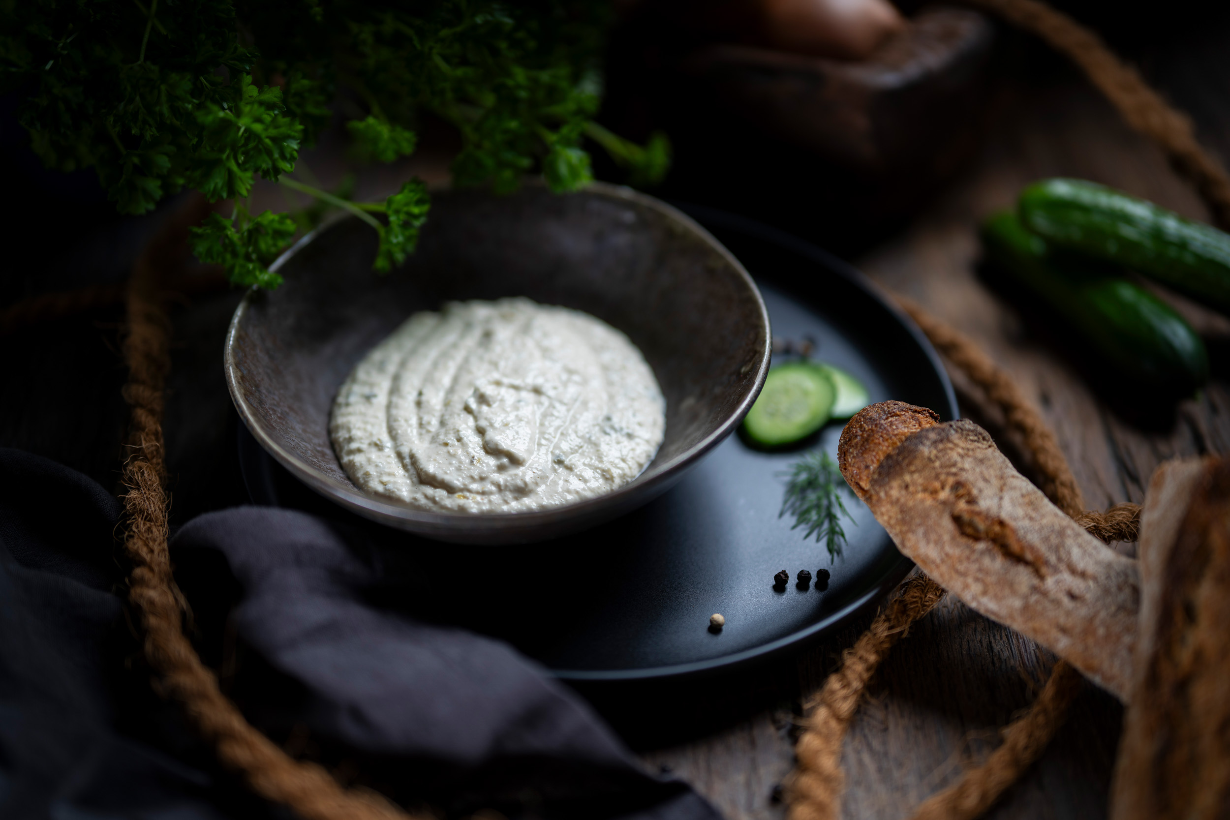 Cremige Remoulade in dunkler Schale, rustikal präsentiert mit Brot und Kräuter-Akzenten.
