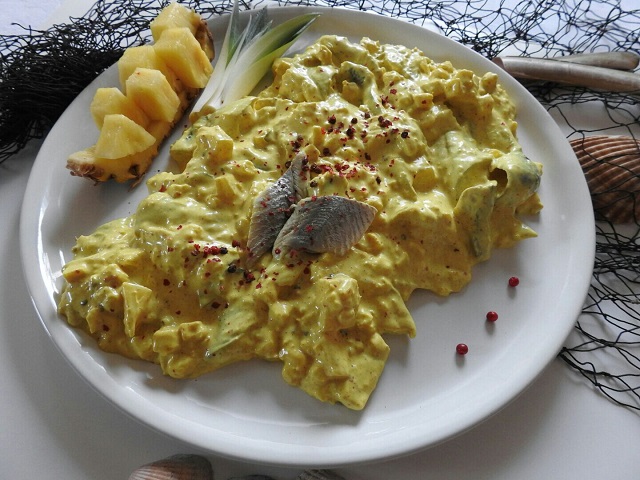 Heringssalat Indonesia Heringssalat Indonesia in Currysauce mit Ananas & rotem Pfeffer, frisch auf weißem Teller.