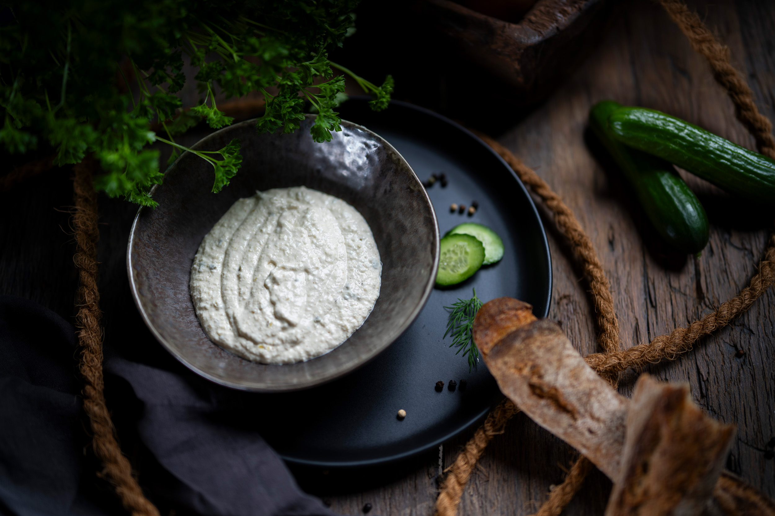 Cremige Remoulade in dunkler Schale, rustikal präsentiert mit Brot und Kräuter-Akzenten.