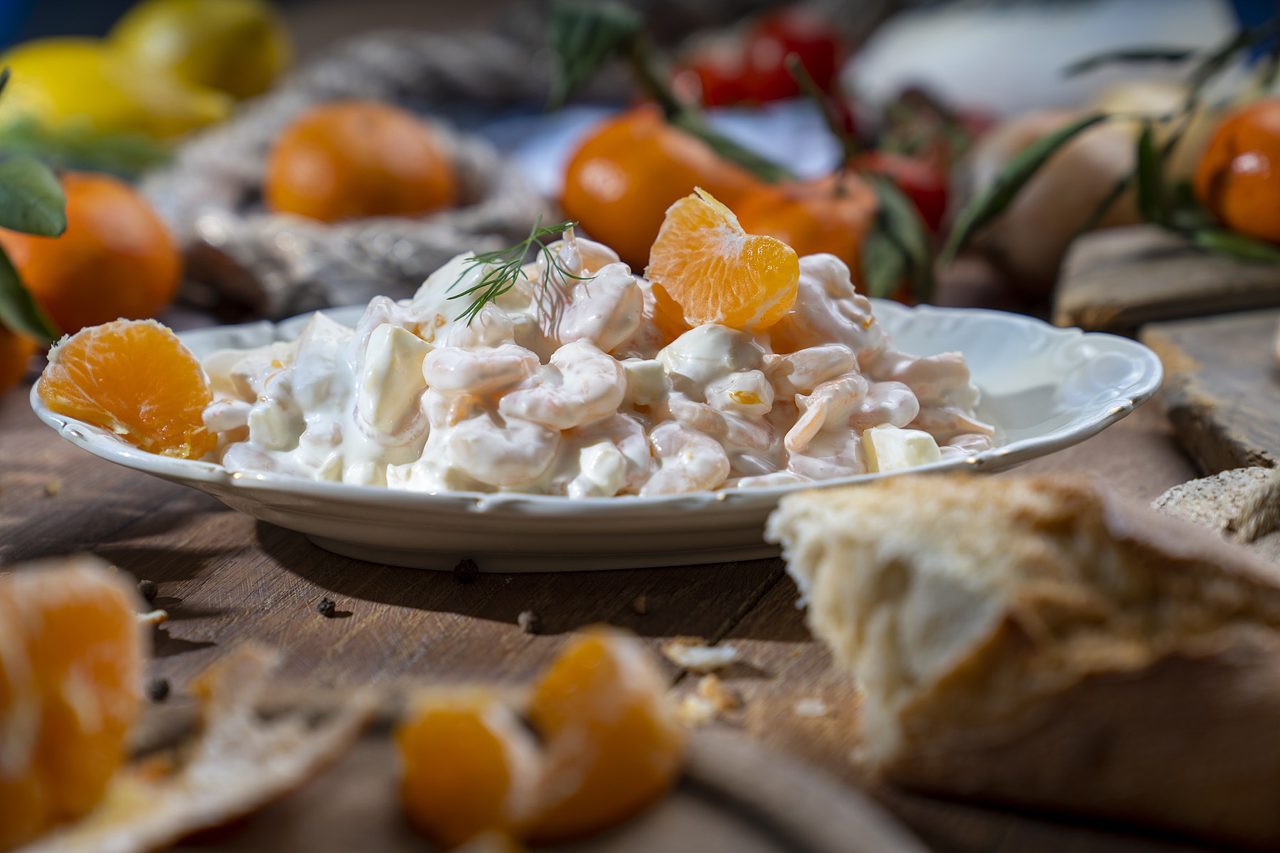 Garnelen in Mayonnaise auf Teller, garniert mit Mandarinenstücken und frischem Dill.