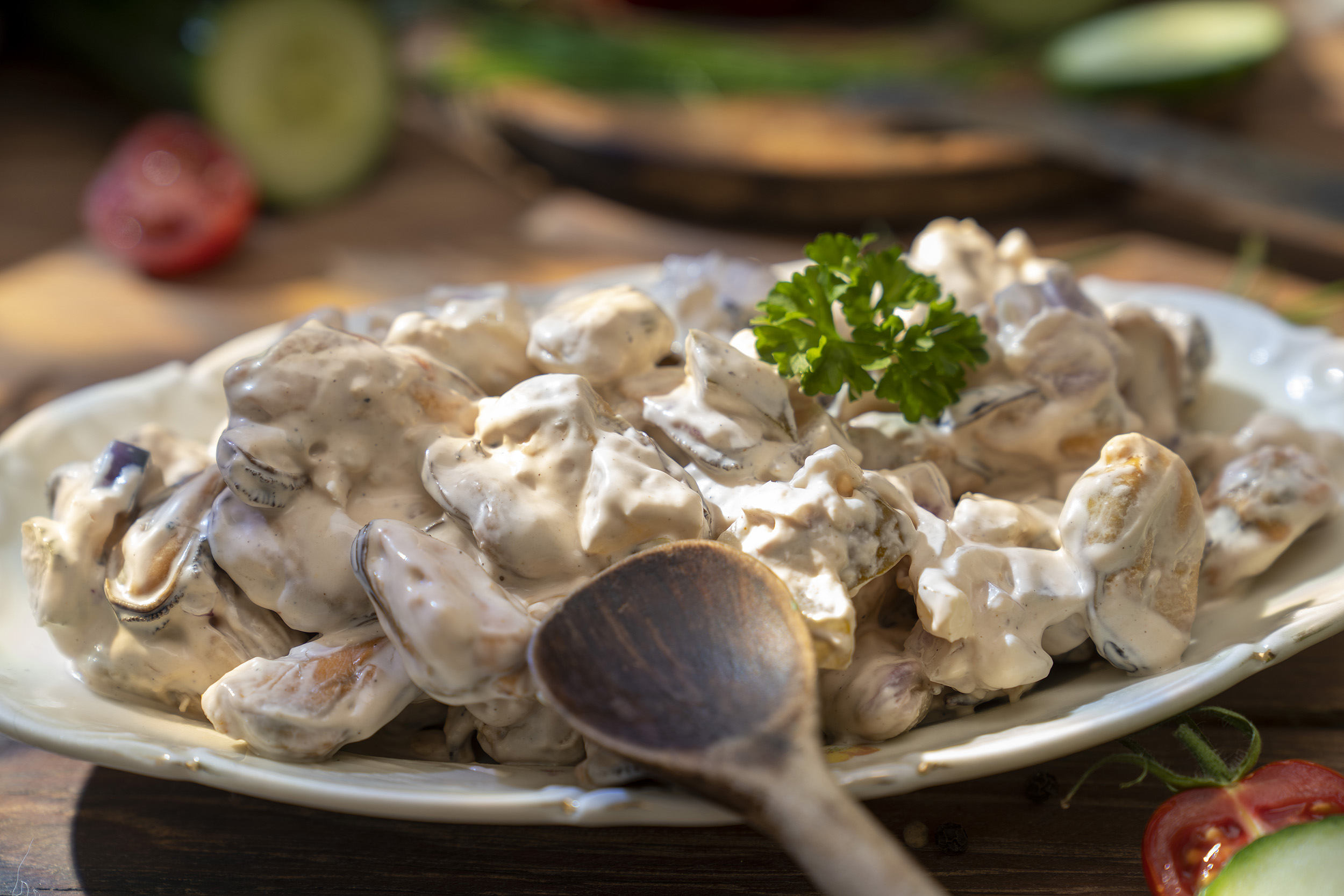 Muschelsalat Coruna Muschelsalat mit Mayonnaise, garniert mit Petersilie auf weißem Teller serviert.