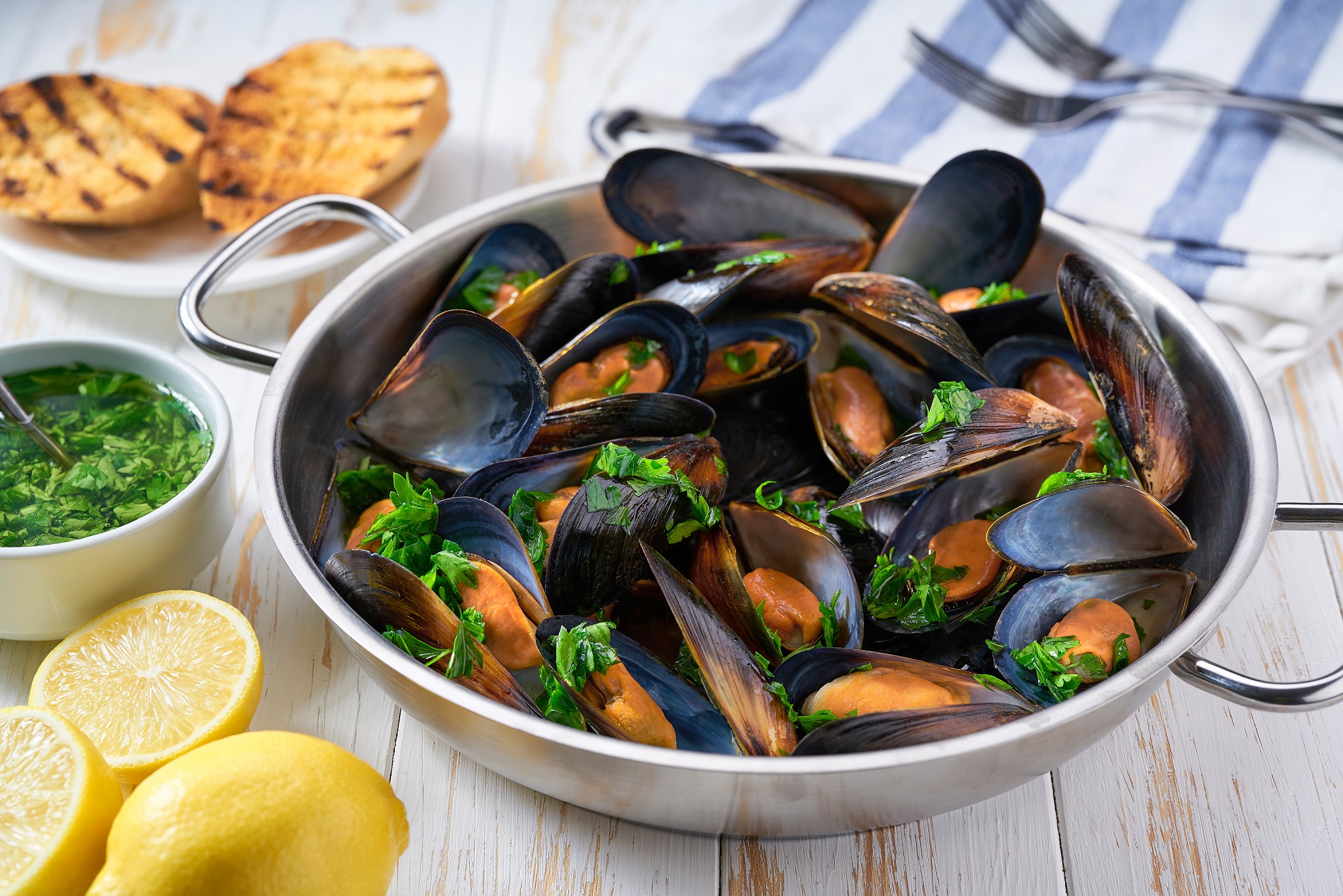 Frische Miesmuscheln in Topf mit Kräutern, Zitronen und Dips – maritimer Genuss.
