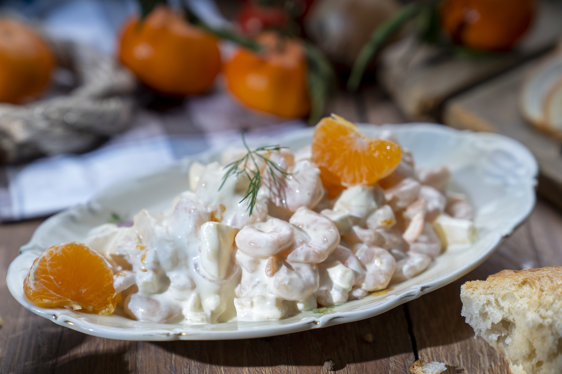 Garnelen in Mayonnaise auf Teller, garniert mit Mandarinenstücken und frischem Dill.