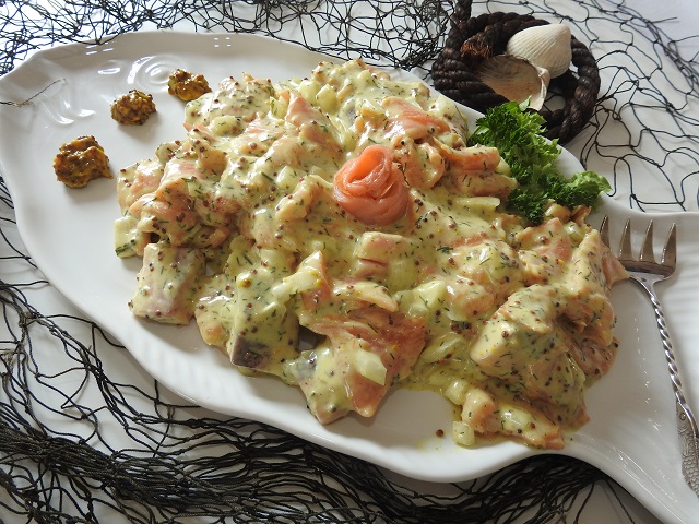 Räucherlachssalat 'Wikinger' Cremiger Wikinger-Salat mit Lachs-Stücken, Apfel und Dill auf weißem Fisch-Teller, maritim dekoriert.