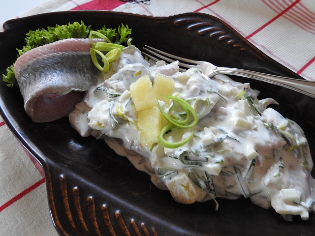 Skipper-Fischsalat mit zarten Fischstücken, frischen Kräutern und Gewürzgurke auf Teller
