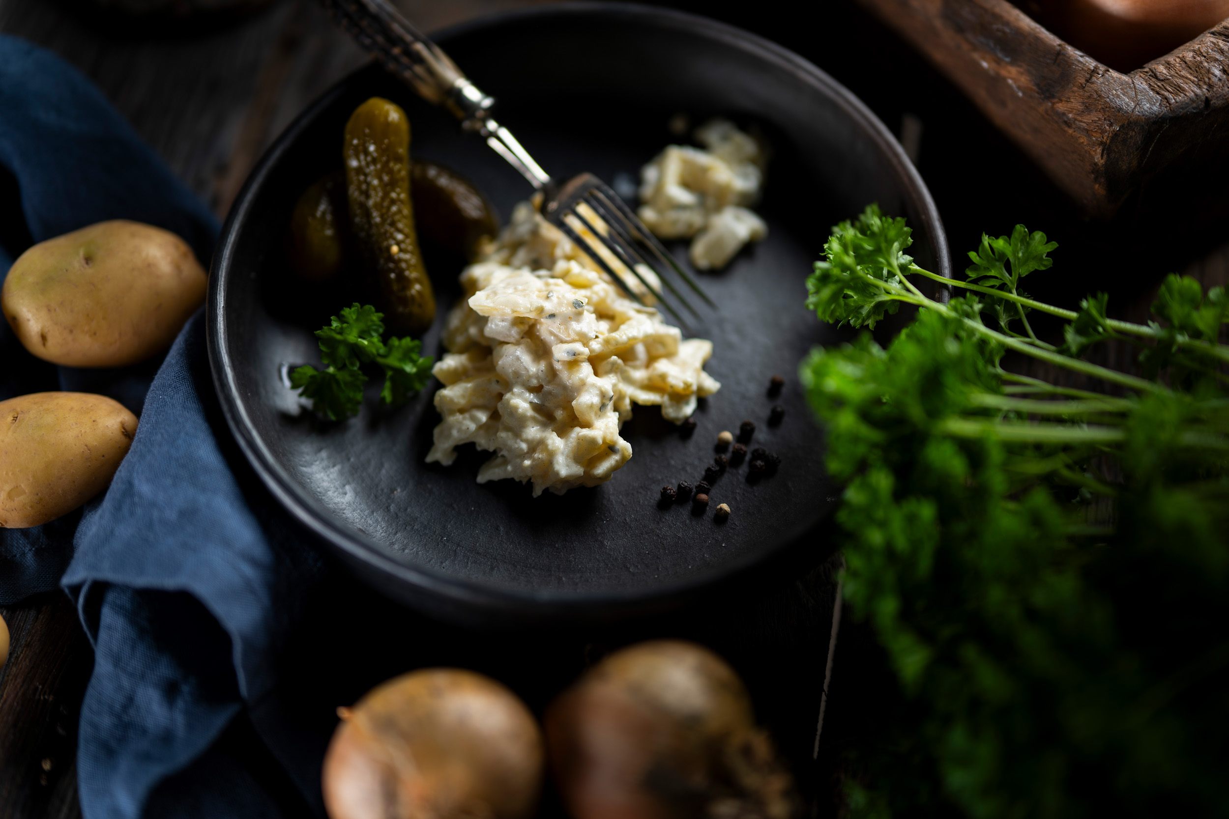 Hausgemachter Kartoffelsalat in cremiger Salat-Mayonnaise, garniert mit frischen Gurkenstücken.