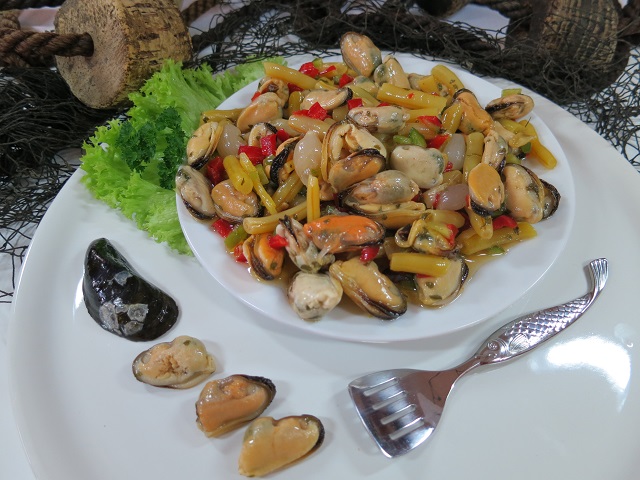 Muschelsalat mit buntem Gemüse und Petersilie auf weißem Teller – frisch, maritim serviert
