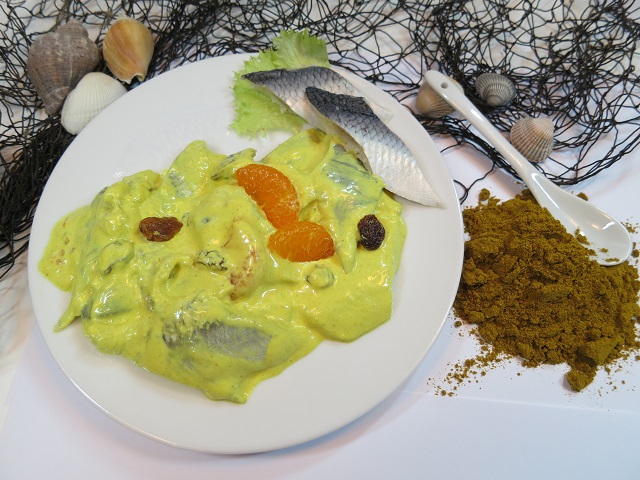Curry-Happen Curry-Happen: Matjesstücke in gelber Currysauce mit Mandarine und Rosinen, maritim dekoriert.