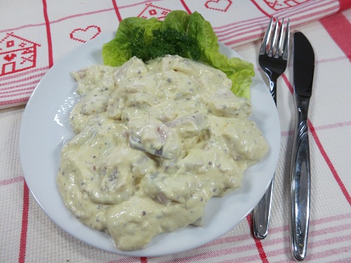 Matjesschmaus Helsinki Cremiger Fischsalat mit Senf-Dressing auf weißem Teller, garniert mit grünem Salatblatt