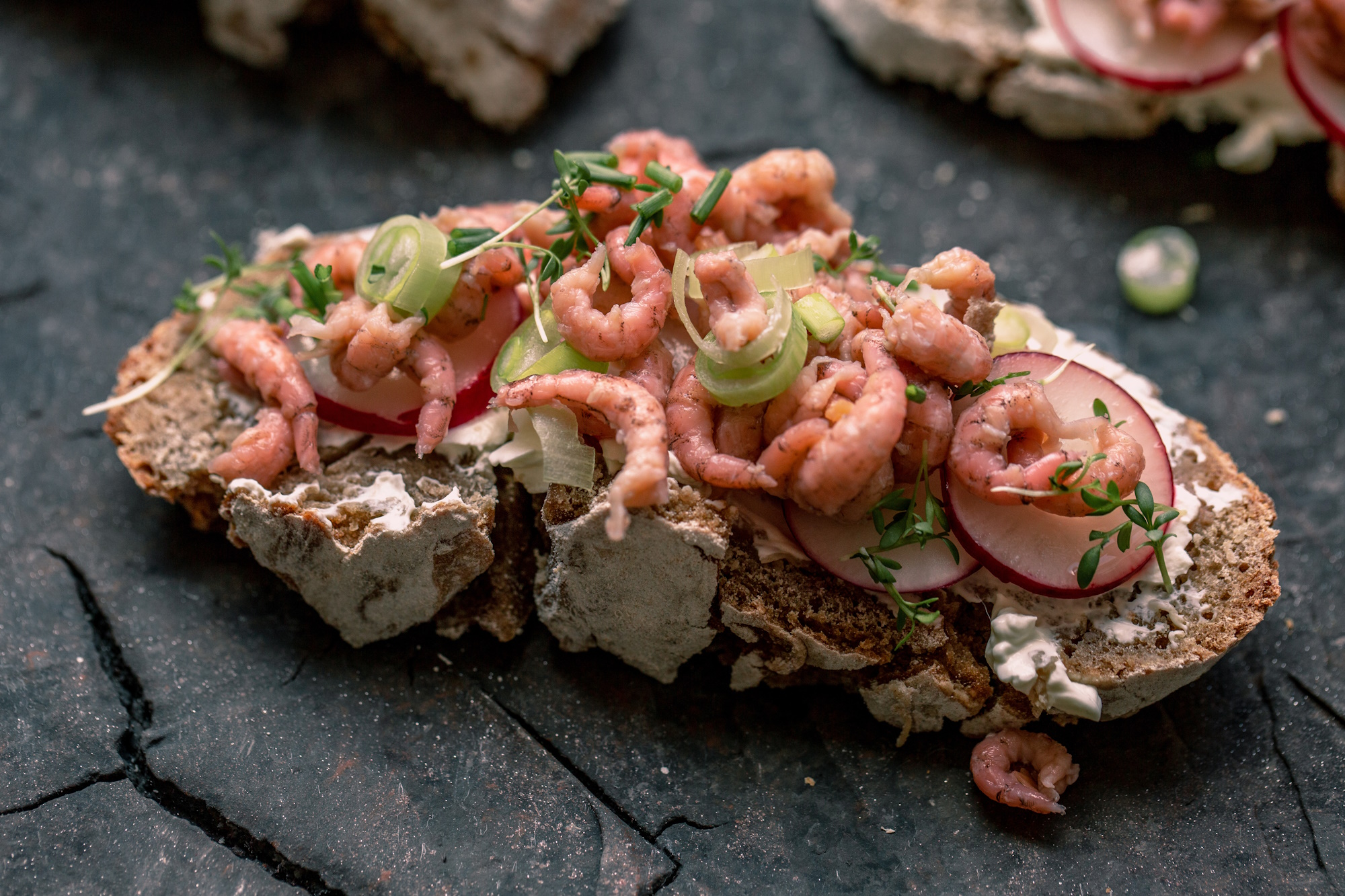 Nordseekrabben auf knusprigem Brot mit Schnittlauch, Lauchzwiebeln & Radieschen garniert.